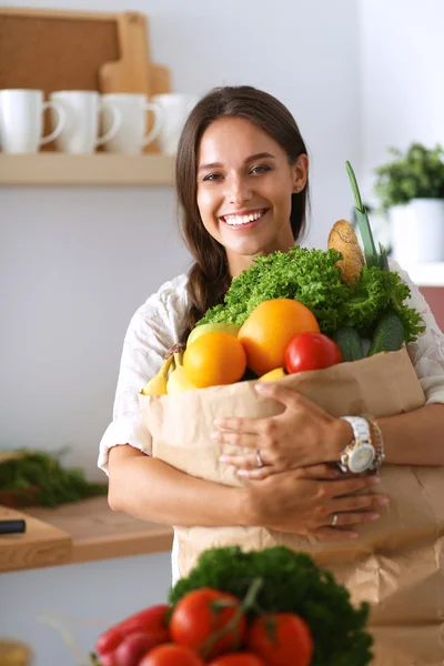Elinde sebzeli alışveriş torbası tutan genç bir kadın. — Stok fotoğraf