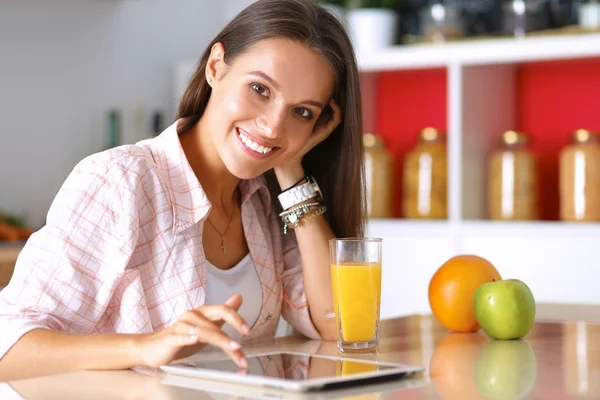 女性彼女のキッチンでお茶を飲みながらタブレット コンピューターを使用して — ストック写真