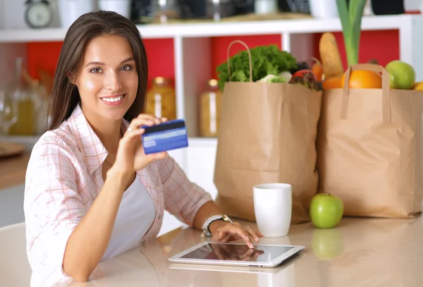 Smiling woman online shopping using tablet and credit card in kitchen — Stock Photo, Image