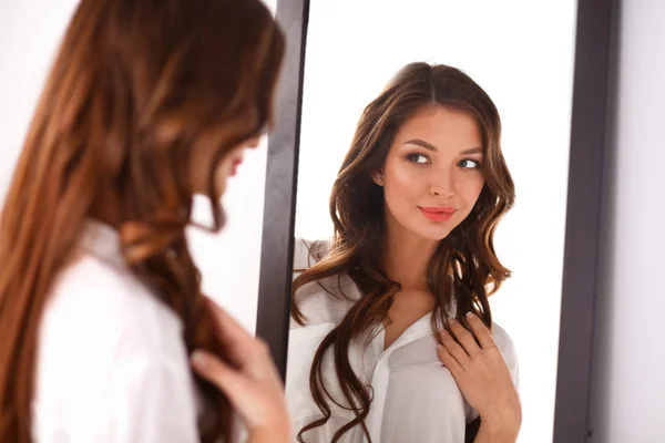 Молодая женщина смотрит на себя отражение в зеркале дома — стоковое фото