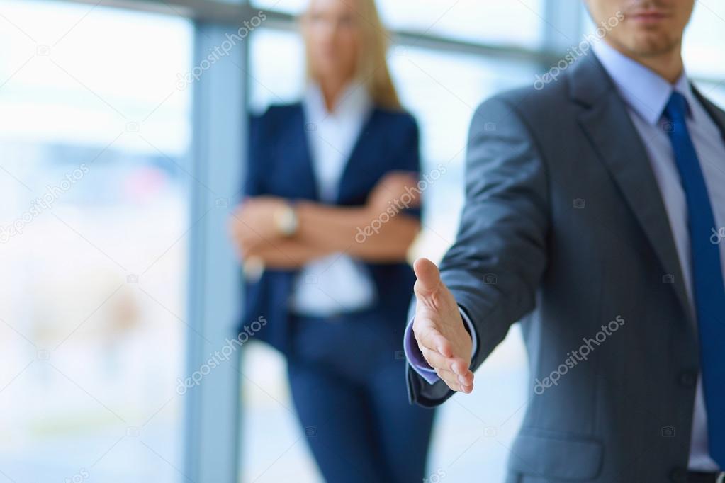 Young businessman ready to handshake standing in office