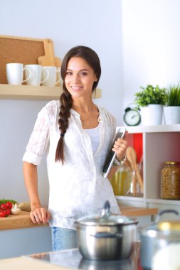 Mutfakta yemek yapmak için tablet bilgisayar kullanan genç bir kadın.