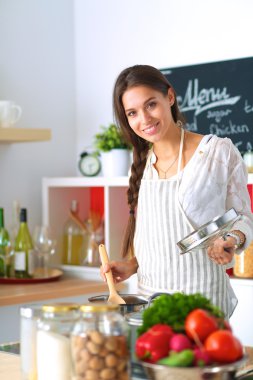 Mutfakta ahşap kaşıkla yemek pişiren kadın