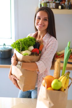 Elinde sebzeli alışveriş torbası tutan genç bir kadın.