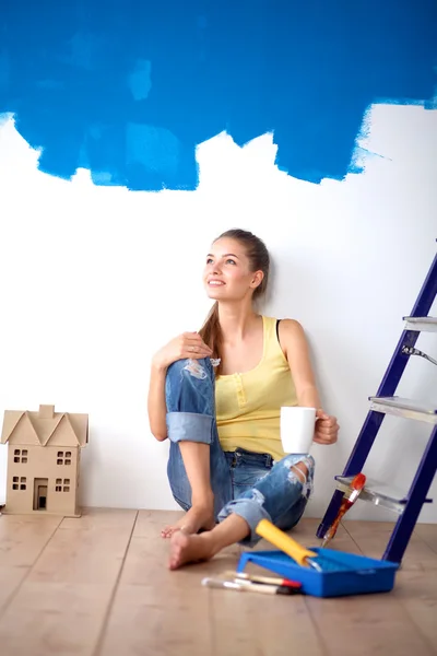 Porträt einer Malerin, die nach dem Malen auf dem Boden neben der Wand sitzt. — Stockfoto