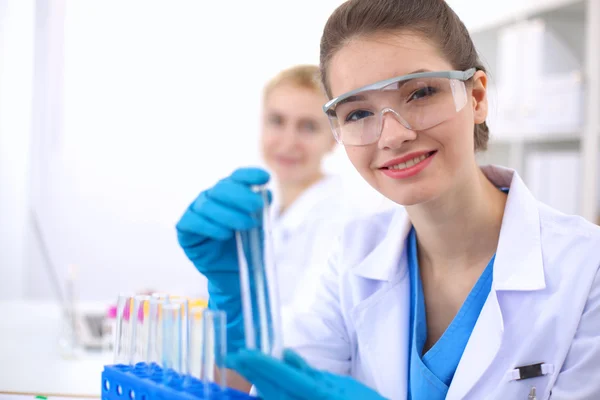 Woman researcher is surrounded by medical vials and flasks, isolated on white background — Stock Photo, Image