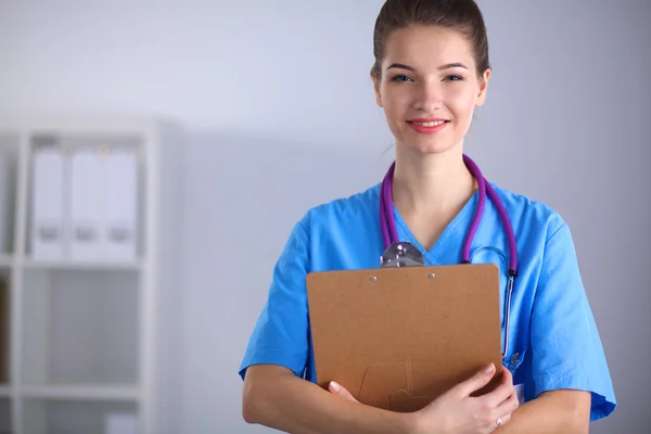 Lächelnde Ärztin mit Ordner in Uniform steht im Krankenhaus — Stockfoto