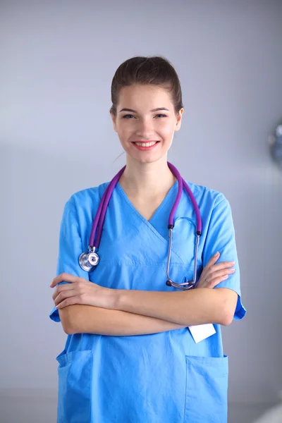 Médecin souriante avec un dossier en uniforme debout à l'hôpital — Photo