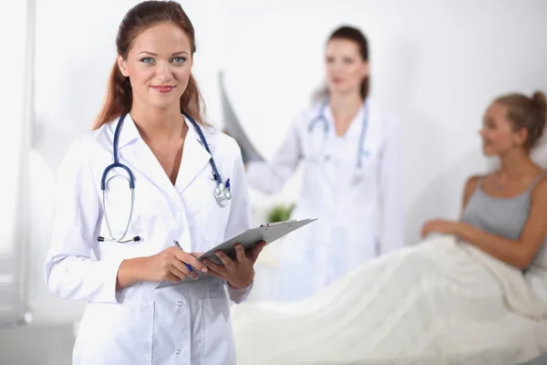 Médico sonriente con una carpeta en uniforme de pie en el hospital —  Fotos de Stock