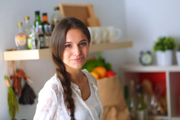 Jovem mulher de pé perto da mesa na cozinha — Fotografia de Stock