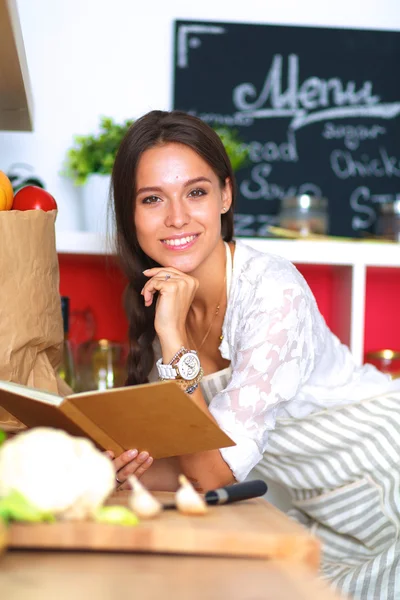 Giovane donna che legge il libro di cucina, alla ricerca di ricetta — Foto Stock