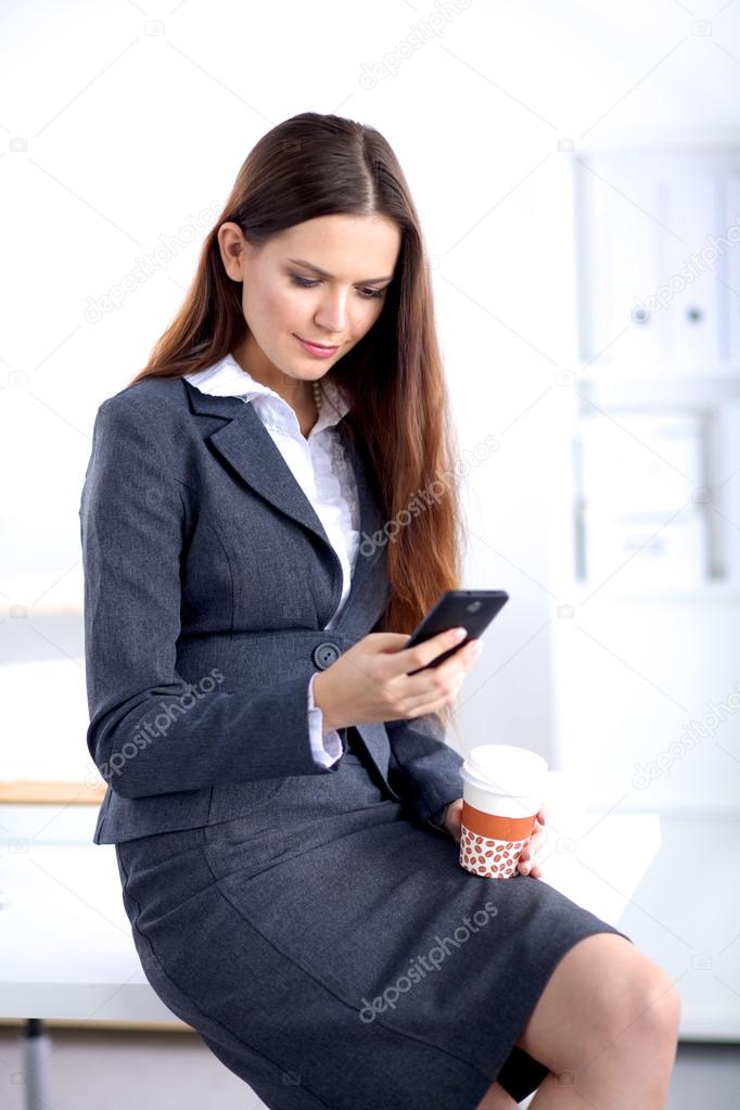 Businesswoman sending message with smartphone sitting