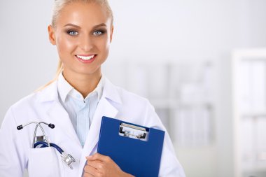 Çekici genç iş kadını masanın yanında elinde dosyayla duruyor.