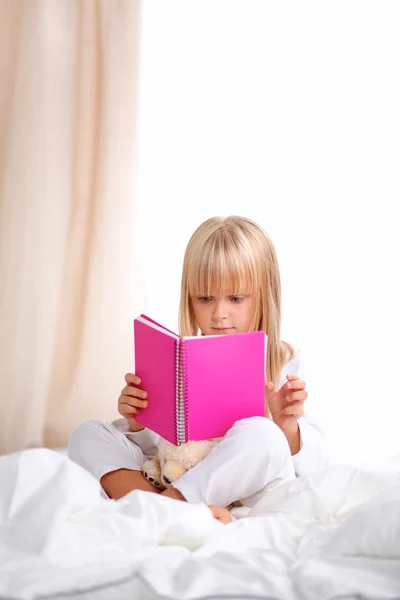 Menina deitada na cama e lendo um livro — Fotografia de Stock