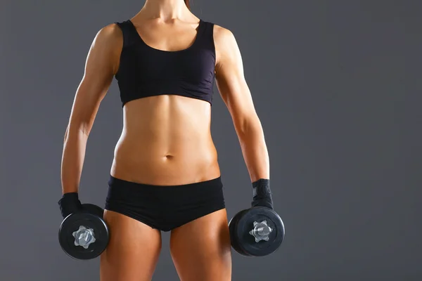 Athletic woman pumping up muscules with dumbbells — Stock Photo, Image