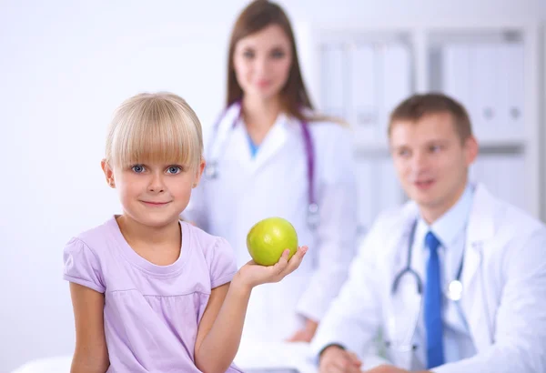 Η έννοια του παιδιού και της ιατρικής - γυναίκα γιατρός δίνει ένα μήλο στο κοριτσάκι — Φωτογραφία Αρχείου