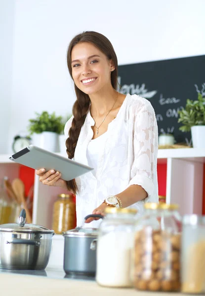 Junge Frau kocht mit Tablet-Computer in ihrer Küche — Stockfoto