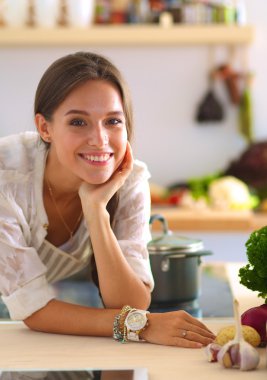 Mutfakta yemek yapmak için tablet bilgisayar kullanan genç bir kadın.