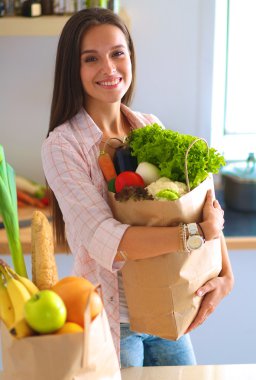 Elinde sebzeli alışveriş torbası tutan genç bir kadın.