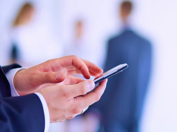 Portret van jonge zakenman mobiele gebruiken in office met collega's op de achtergrond — Stockfoto