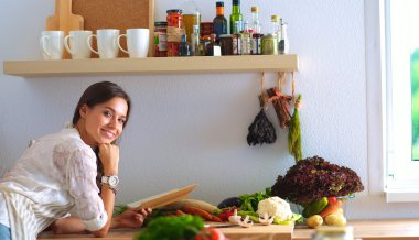 Mutfakta yemek kitabı okuyan genç bir kadın yemek tarifi arıyor.