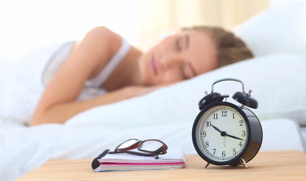 Jonge slapende vrouw en wekker in slaapkamer thuis — Stockfoto