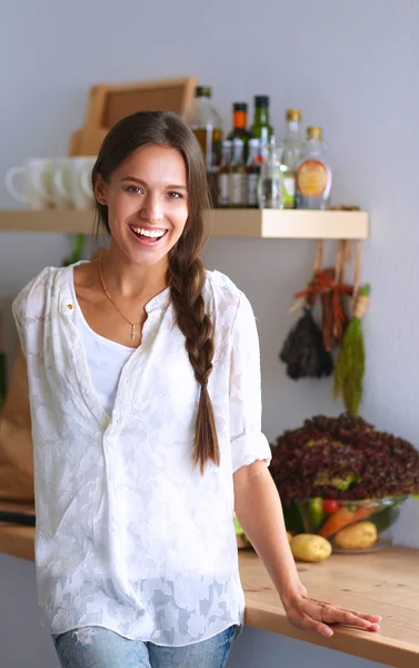 Jovem mulher de pé perto da mesa na cozinha — Fotografia de Stock