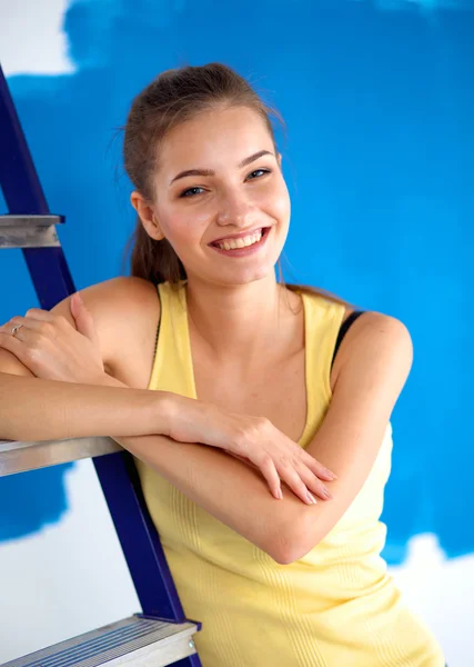 Hermosa mujer joven haciendo pintura de pared, de pie cerca de la escalera — Foto de Stock