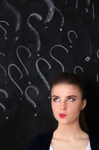 Young girl with question mark on a gray background — Stock Photo, Image