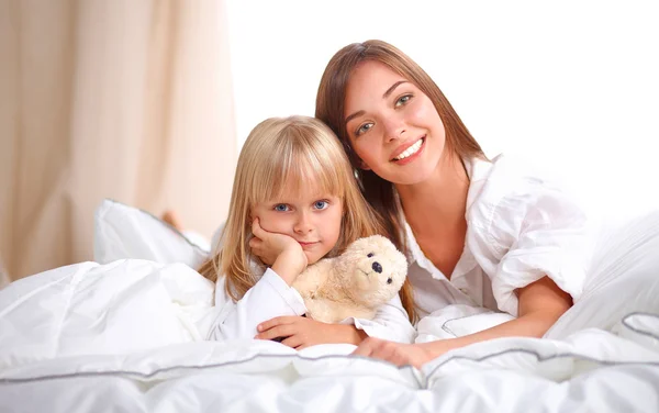 Woman and young girl lying in bed smiling — Stock Photo, Image