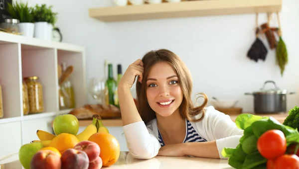 Jonge vrouw zit in de buurt van bureau in de keuken — Stockfoto