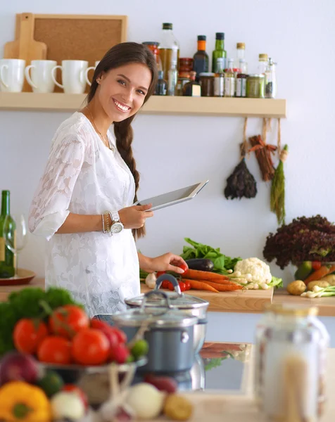 Jonge vrouw met behulp van een tablet computer om te koken in haar keuken — Stockfoto