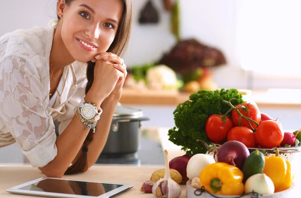 Jovem usando um computador tablet para cozinhar em sua cozinha — Fotografia de Stock