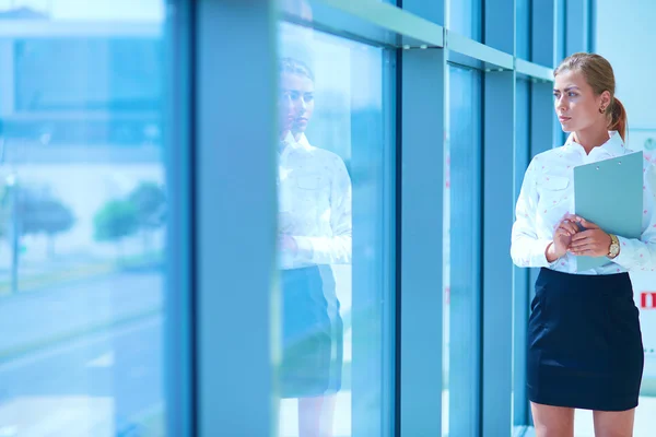 Imprenditrice in piedi contro la finestra dell'ufficio in possesso di documenti in mano — Foto Stock
