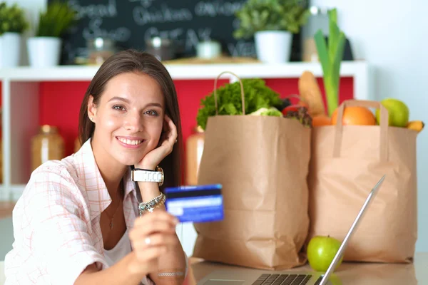 Femme souriante achats en ligne en utilisant tablette et carte de crédit dans la cuisine — Photo