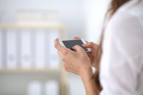 Zakenvrouw stuurt bericht met smartphone zittend op kantoor — Stockfoto