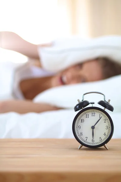 Joven mujer dormida y despertador en el dormitorio en casa —  Fotos de Stock