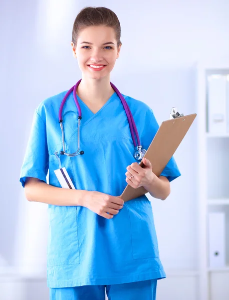 Médico sonriente con una carpeta en uniforme de pie en el hospital — Foto de Stock