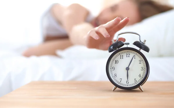 Jeune femme endormie et réveil dans la chambre à coucher à la maison — Photo