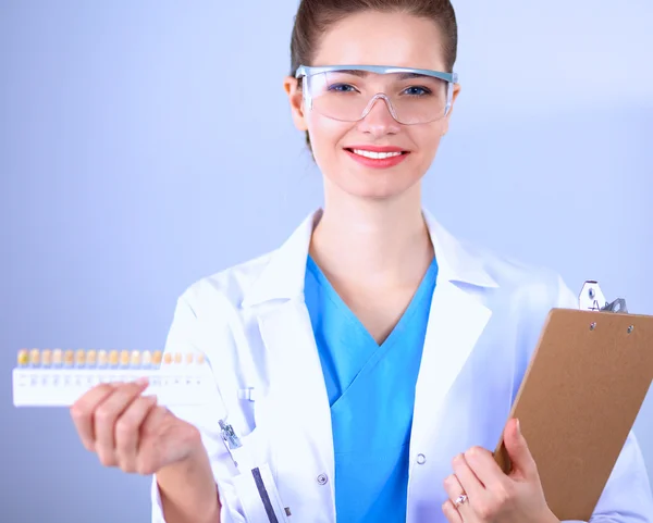 Médico sonriente con una carpeta en uniforme de pie en el hospital — Foto de Stock