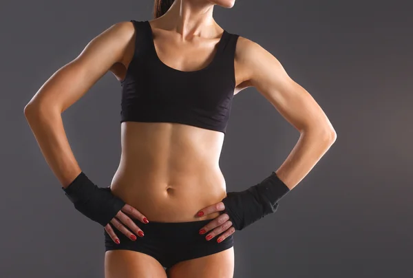 Muscular young woman  standing on gray background — Stock Photo, Image