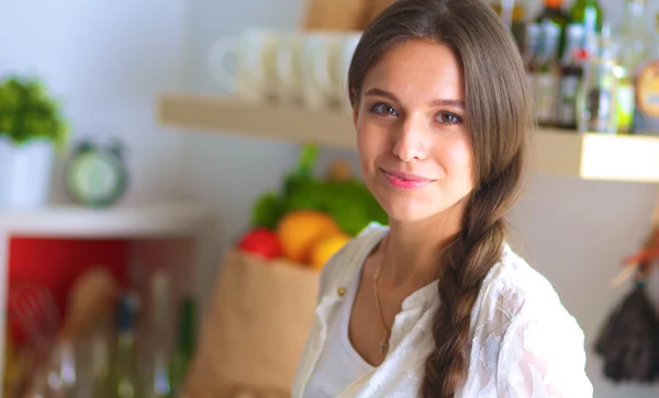 Jovem mulher de pé perto da mesa na cozinha — Fotografia de Stock