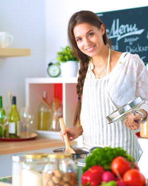 Mutfakta ahşap kaşıkla yemek pişiren kadın