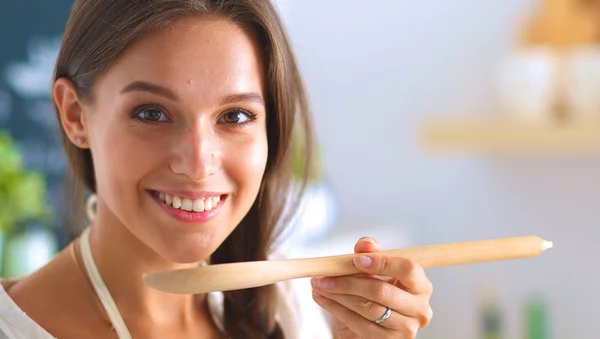 Mujer cocinera en cocina con cuchara de madera —  Fotos de Stock