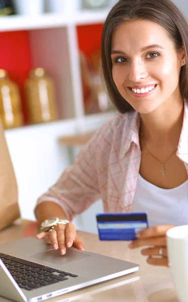 Mujer sonriente compras en línea utilizando la tableta y la tarjeta de crédito en la cocina —  Fotos de Stock