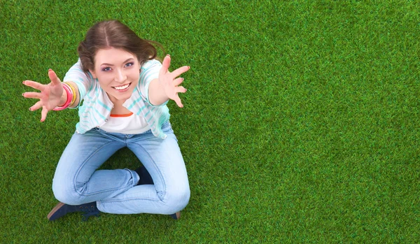 Ovansida av vacker ung kvinna som sitter på det gröna gräset — Stockfoto