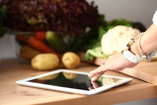 Mujer joven usando una tableta para cocinar en su cocina — Foto de Stock