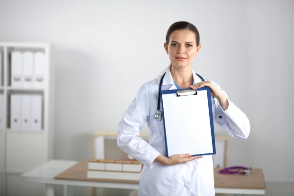 Lächelnde Ärztin mit Ordner in Uniform steht im Krankenhaus — Stockfoto