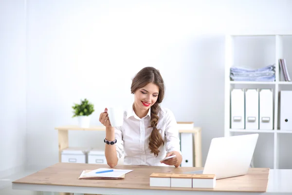 Attraktive Geschäftsfrau sitzt auf Schreibtisch im Büro — Stockfoto