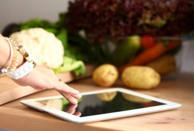 Gülümseyen kadın mutfakta tablet ve kredi kartı kullanarak alışveriş online